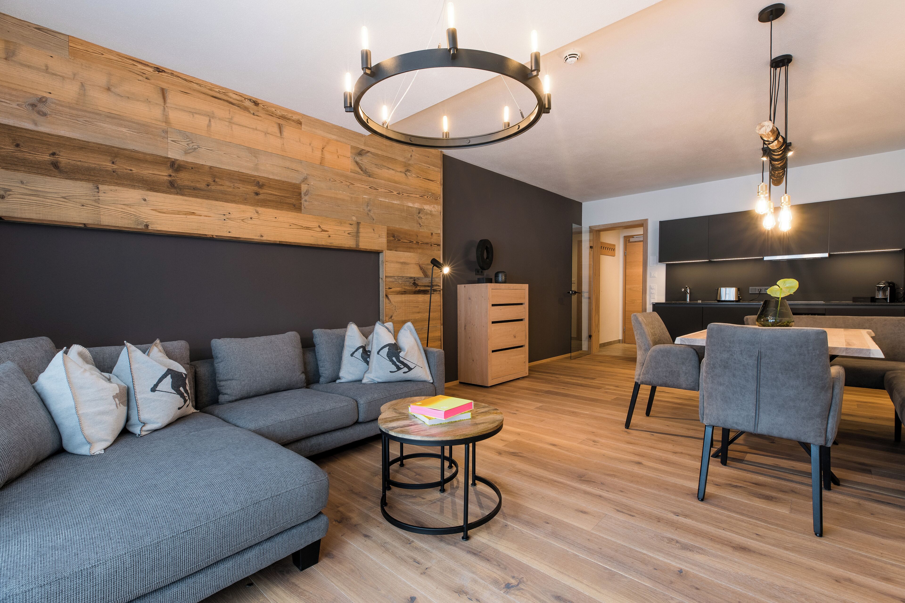 A modern living room with a sectional sofa, a small round table, and a dining area with chairs.