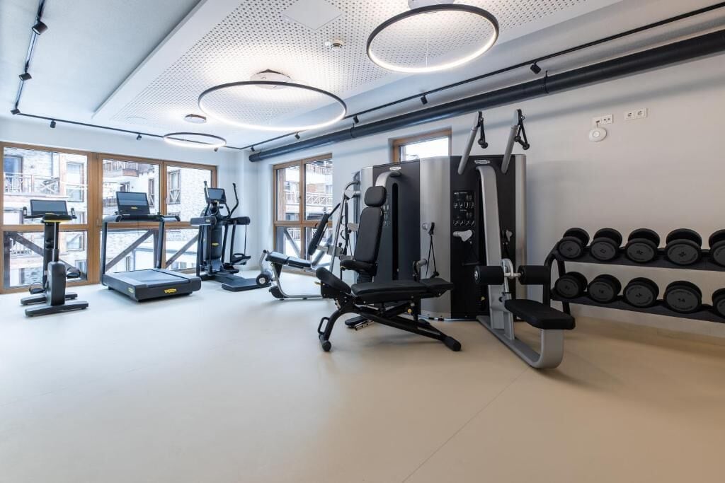A gym with treadmills, weight machines, and dumbbells.