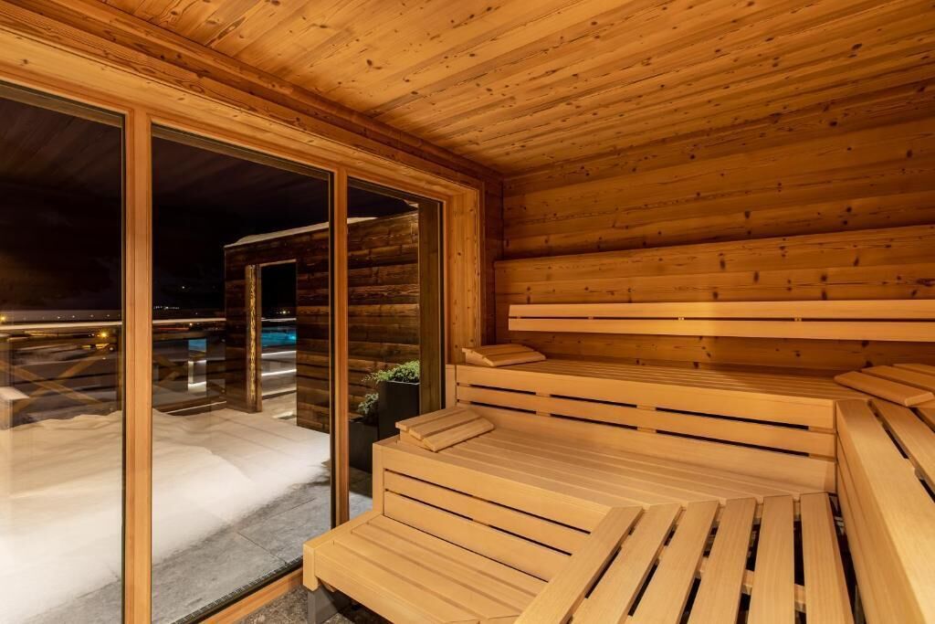 A wooden sauna with benches and a glass door leading outside.