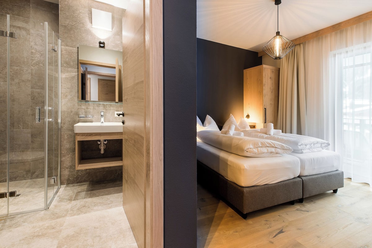 Een moderne badkamer met een glazen douchecabine, een houten wastafelmeubel en een grote spiegel.