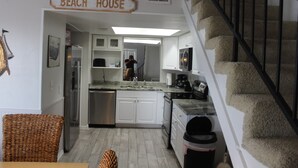 A kitchen with white cabinets, a stainless steel refrigerator, and a sign that reads 'Beach House.' - Brower's Lagoon Run at the Beach (Gulf Shores)