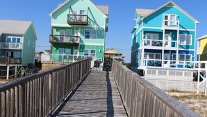 A wooden boardwalk leading to colorful beach houses with balconies. - Brower's Lagoon Run at the Beach (Gulf Shores)