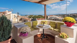 Una terraza en la azotea con zona de estar, una mesa y plantas en macetas.