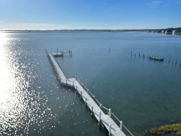 A pier extending into calm water with a clear sky above. - Assateague Point - Dynamic Waterfront ,Pier,Dock, LINENS AND TOWELS PROVIDED (Chincoteague)
