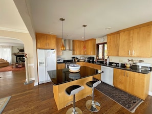 A modern kitchen with wooden cabinets, a black countertop, and two bar stools.