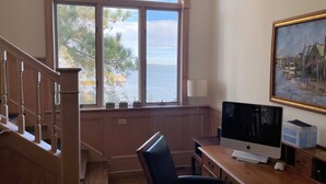 A room with a desk, computer, and a large window overlooking a body of water. - Assateague Point - Dynamic Waterfront ,Pier,Dock,  LINENS AND TOWELS PROVIDED (Chincoteague)