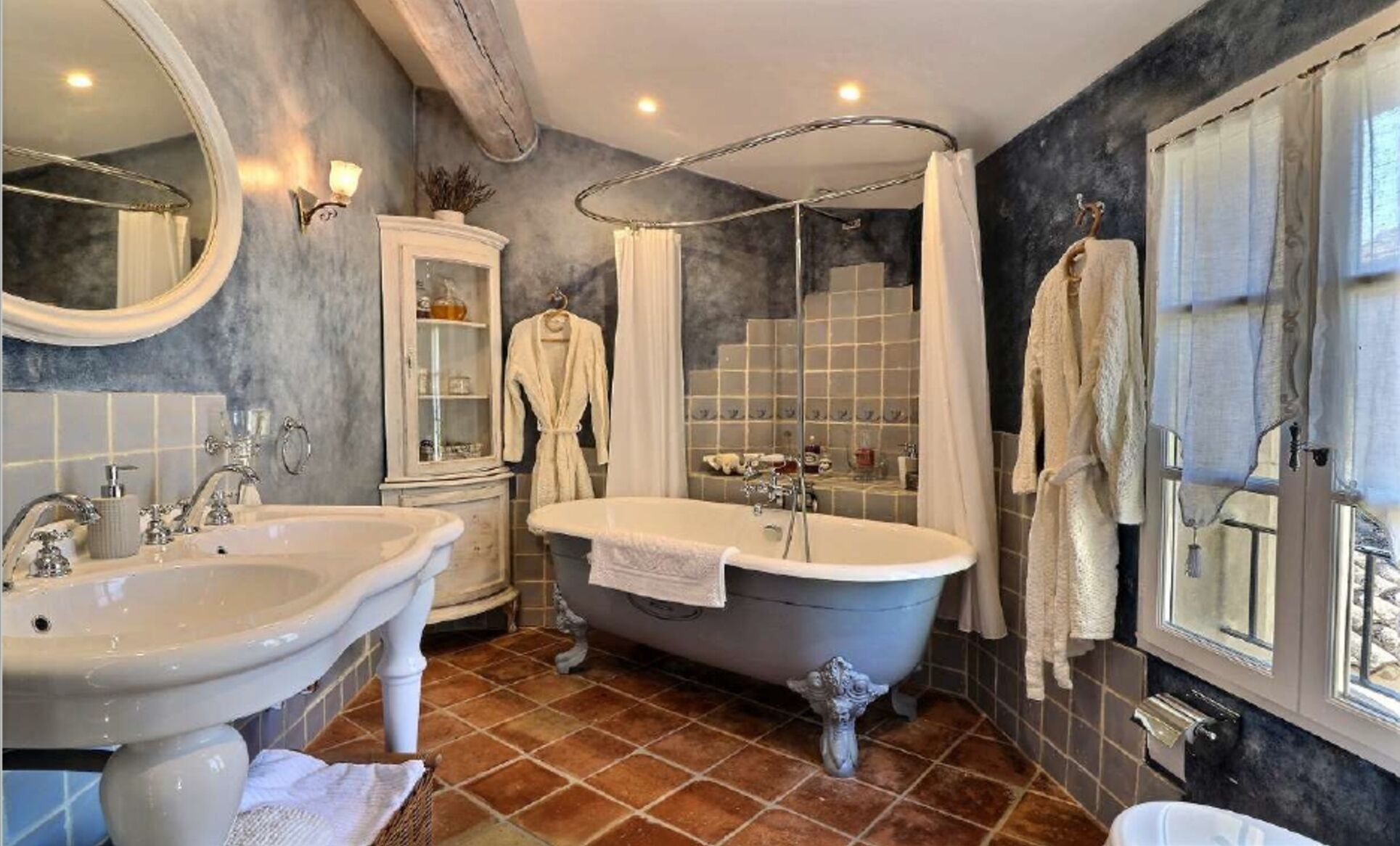 Une salle de bain avec une baignoire sur pieds, deux lavabos, un meuble-lavabo et un grand miroir.