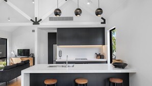 Een moderne keuken met een centraal eiland, barstoelen en hanglampen.