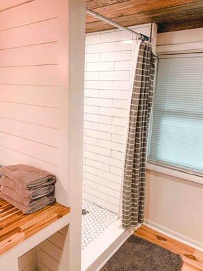 Ein Badezimmer mit Dusche, Handtuchhalter und einem Fenster mit Jalousien.