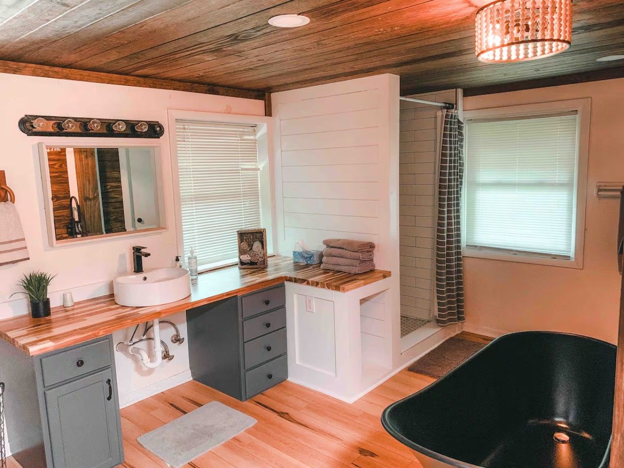 Un baño moderno con tocador de madera, un lavabo, un espejo, zona de ducha y bañera.