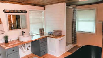 Un baño moderno con tocador de madera, un lavabo, un espejo, zona de ducha y bañera.