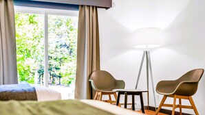 A hotel room with a bed, a small table, two chairs, a floor lamp, and a window with curtains. - Mersey River Chalets a nature retreat (Maitland Bridge)