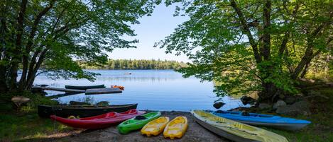 A lakeside view with several kayaks and canoes parked on the shore.