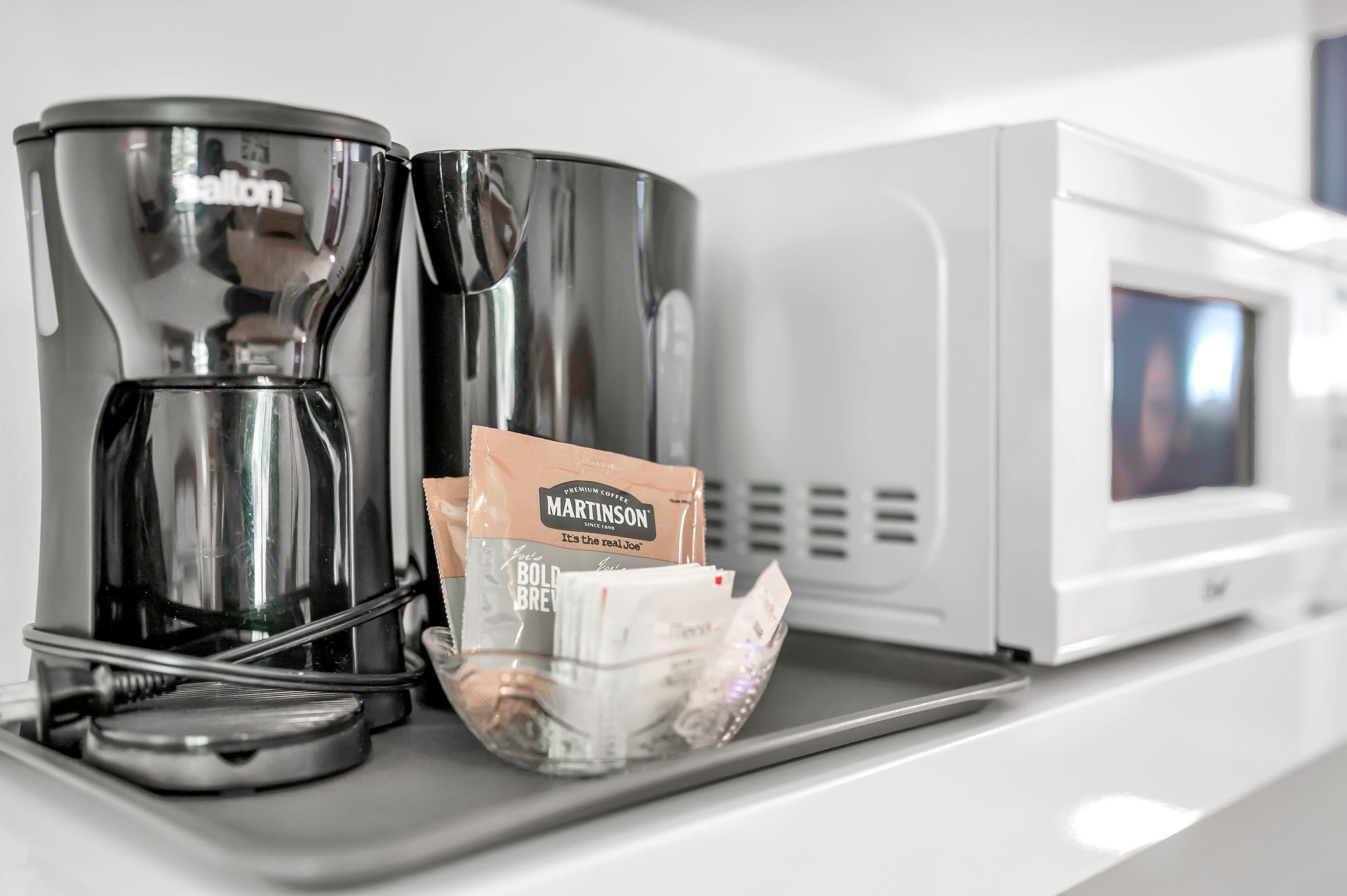 Een koffiezetapparaat, een koffiepadapparaat en een koffiemachine op een aanrecht.