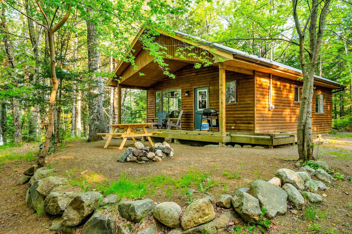 Eine Holzhütte mit Veranda, Picknicktisch und Grill.