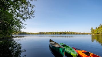 A calm lake with three kayaks docked on the shore.
