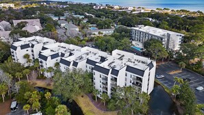A high-rise hotel with multiple floors, a parking lot, and a view of the ocean.