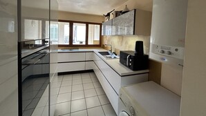 Eine moderne Küche mit eingebautem Backofen, einer Kaffeemaschine und einem Kühlschrank.