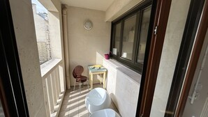 Ein kleiner Balkon mit Tisch, Stühlen und zwei weißen Eimern.