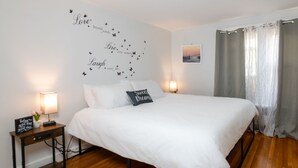 Un dormitorio ordenado con una cama grande, dos mesitas de noche con lámparas, una alfombra mullida y una pared decorada con citas inspiradoras y mariposas.