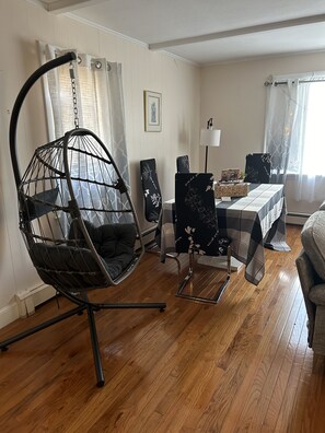 A dining area with a hanging chair, a table with a checkered tablecloth, and chairs with floral upholstery. - Lovely two bedrooms in the great historic town (Salem)