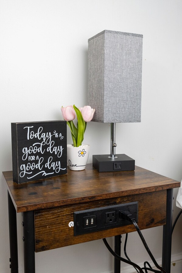 A wooden nightstand with a black sign, a white flower pot, and a grey lamp. - Lovely two bedrooms in the great historic town (Salem)