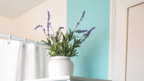 Un estante blanco con toallas azules dobladas y una planta de lavanda en maceta.