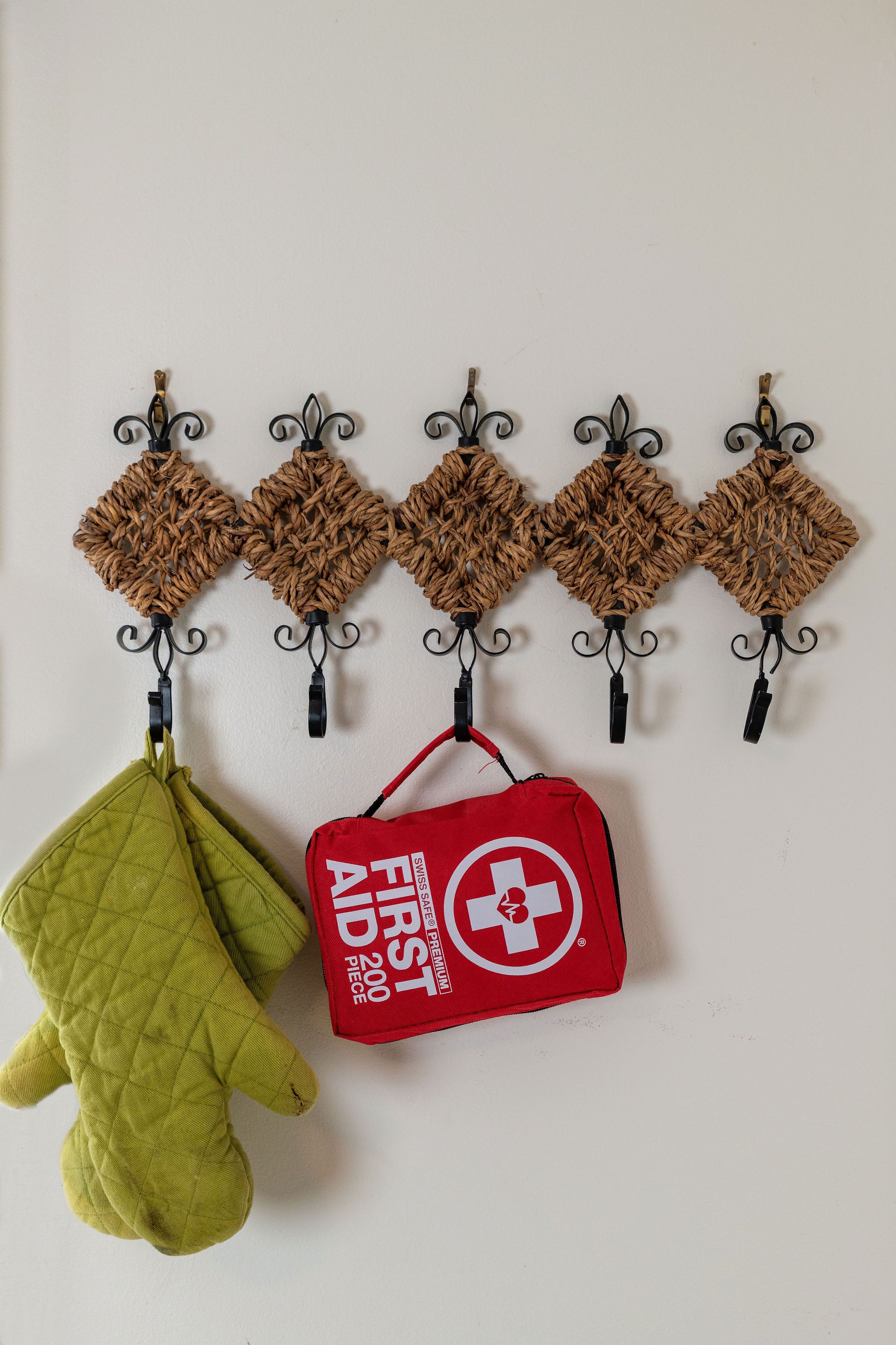 A wall-mounted rack with five brown, textured items and a red first aid kit.