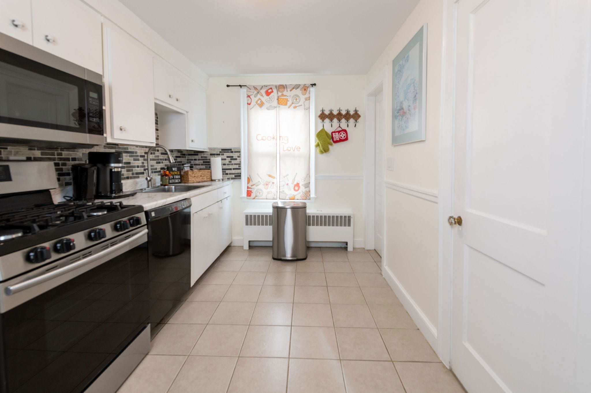 A kitchen with white cabinets, a stainless steel stove, and a microwave.