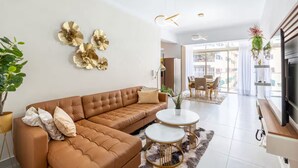 Un salon moderne avec un canapé d’angle marron, deux tables basses rondes et des œuvres d’art décoratives accrochées au mur.