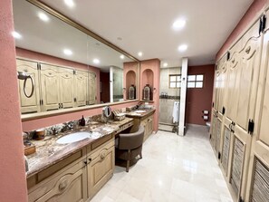 Une salle de bain spacieuse avec deux lavabos, un grand miroir et un espace douche.