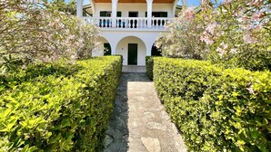 A building with a central courtyard, arched walkways, and a balcony with blue vases. - Astra Beach House in Astrakeri Bay (Astrakeri)