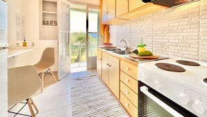 A modern kitchen with wooden cabinets, a white brick backsplash, and a large stove. - Astra Beach House in Astrakeri Bay (Astrakeri)