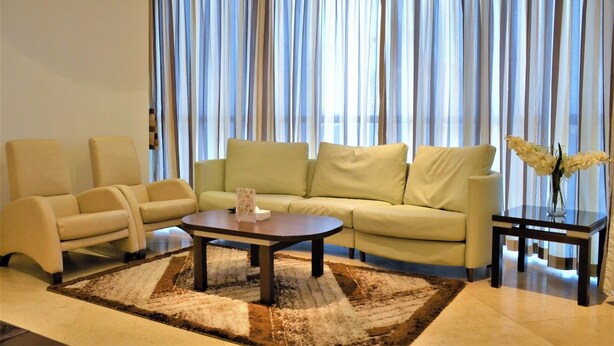 A modern living room with a sofa, two armchairs, a coffee table, and a side table with a vase of flowers. - Butterfly Residence (Manama)