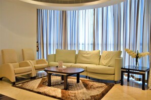 Un salon moderne comprenant un canapé, deux fauteuils, une table basse et une table d’appoint sur laquelle est posé un vase de fleurs.