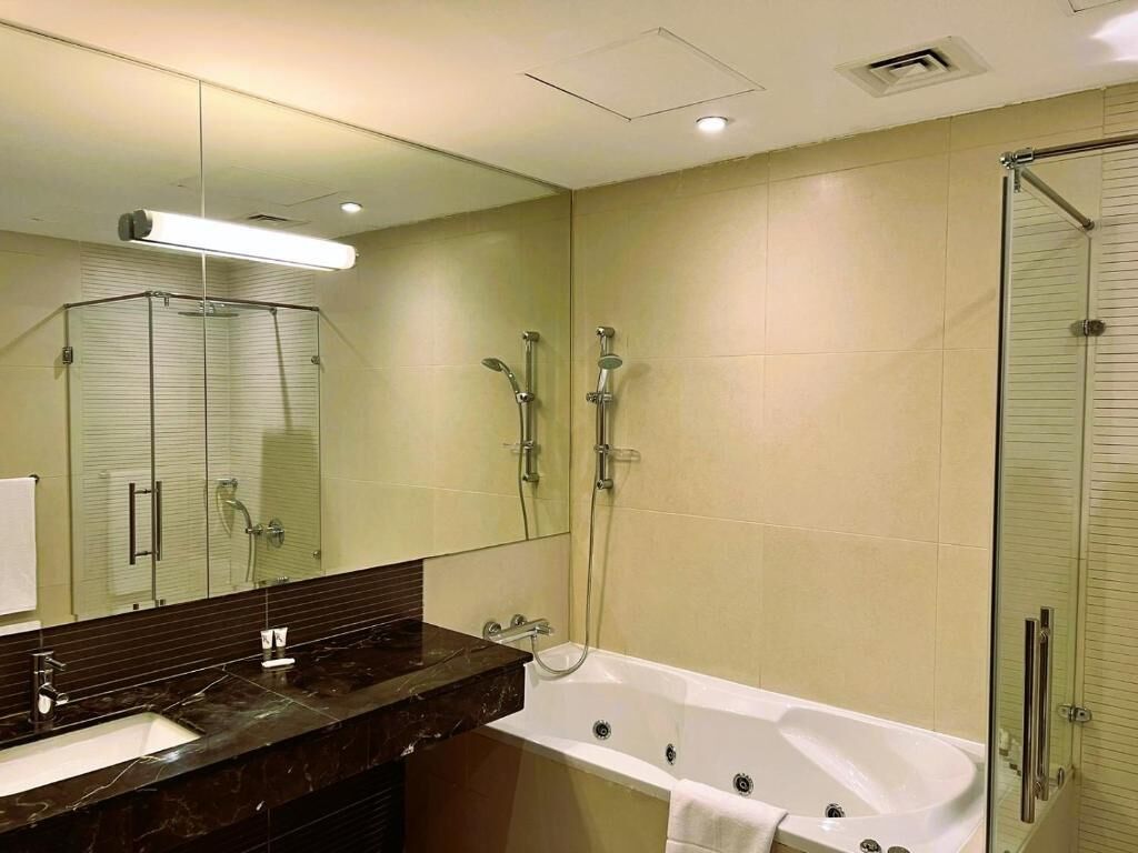 Een moderne badkamer met een grote spiegel, een badkuip, een douche en een wastafelmeubel.