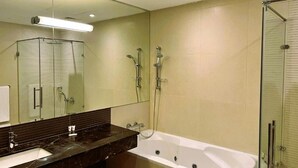 A modern bathroom with a large mirror, a bathtub, a shower area, and a vanity with a sink. - Butterfly Residence (Manama)