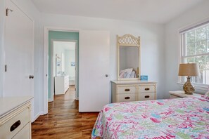 A bedroom with a bed, a dresser, a mirror, and a window.