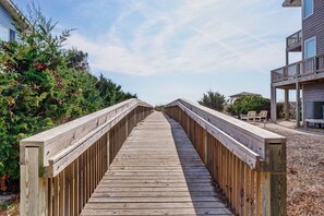 Stroll along the boardwalk surrounded by lush foliage and a nearby building with a balcony.