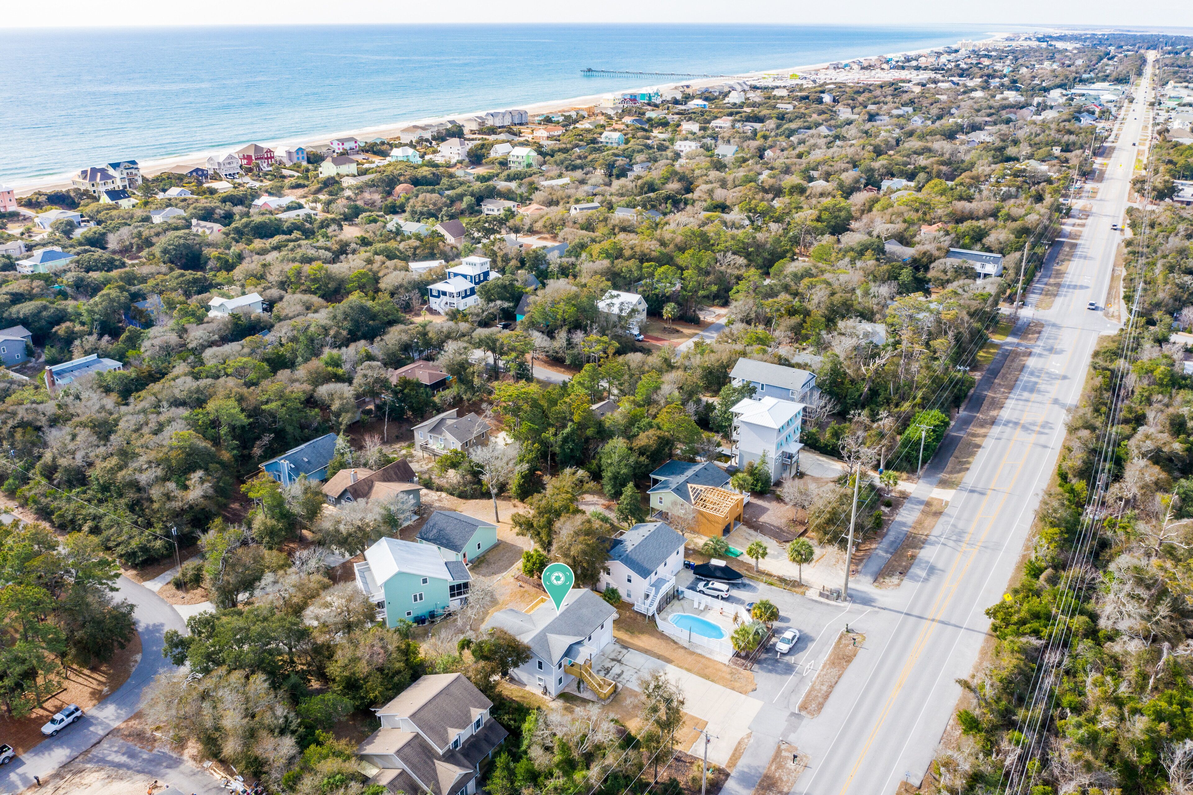 Vue aérienne d’une zone résidentielle côtière, avec des maisons, une route et une plage.