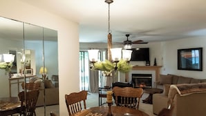 A dining area with a wooden table and chairs, a chandelier, and a fireplace in the background. - Ozark Retreat~Walk-In~Pointe Royale Resort~Pools/Hottub (Branson)