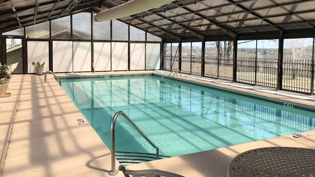 An indoor swimming pool with a covered roof, clear pool water, and a view of the outside. - Ozark Retreat~Walk-In~Pointe Royale Resort~Pools/Hottub (Branson)
