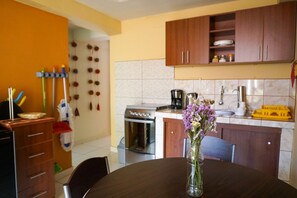A kitchen with wooden cabinets, a stove, and a sink. There is a dining table with a vase of flowers.