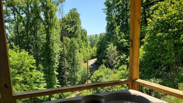 A hot tub with a view of a forested area and a road in the background. - Romantic Getaway! Hot Tub & Mountain Views, King Bed (whittier)