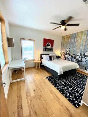 Relax in a serene bedroom with a large bed, ceiling fan, and wall art, perfect for work or study.