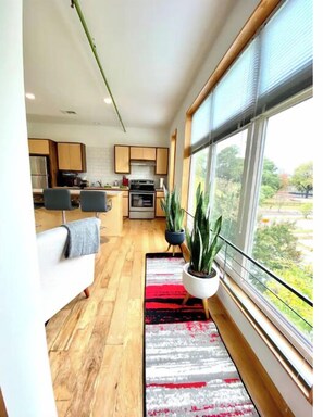 Enjoy a spacious living area with a kitchen, sofa, and large window offering a view of the outdoors.