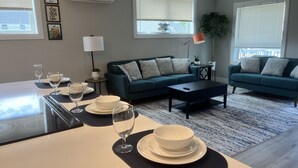 Una sala de estar moderna con comedor, que incluye un conjunto de sofá, una mesa de centro y un juego de mesa listo para una comida.