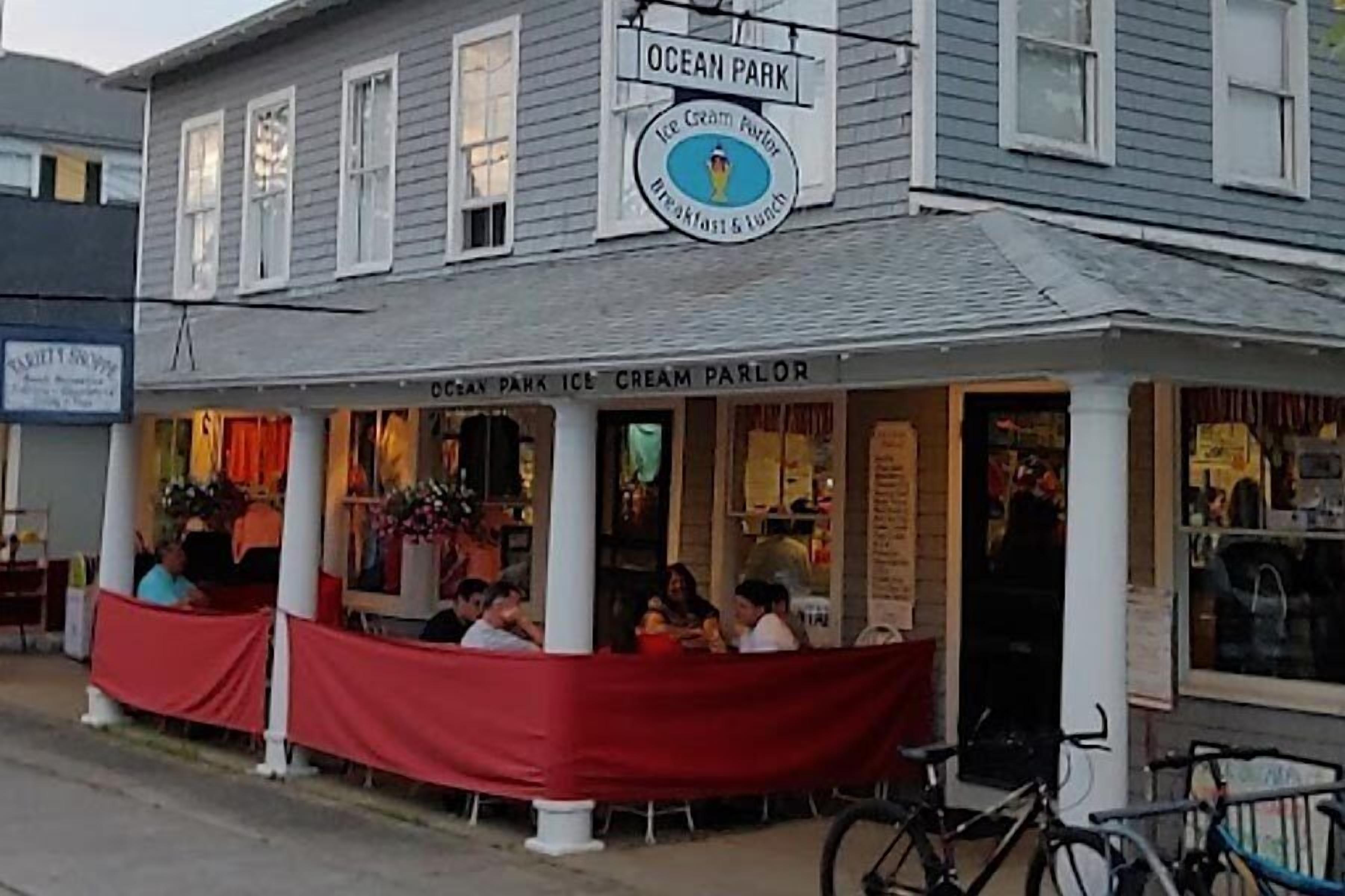 Een gebouw met twee verdiepingen met een bord waarop staat 'Ocean Park Ice Cream Parlor' en een overdekt terras.