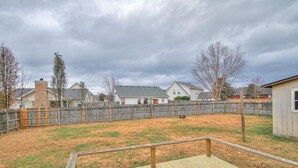 A backyard with a wooden deck, a wooden fence, and houses in the background.