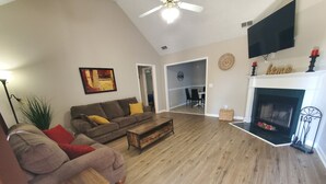 A living room with a sofa, coffee table, fireplace, and a TV mounted on the wall.